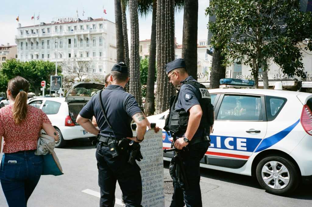 Police officers and a civilian interact near a police car on a busy city street.